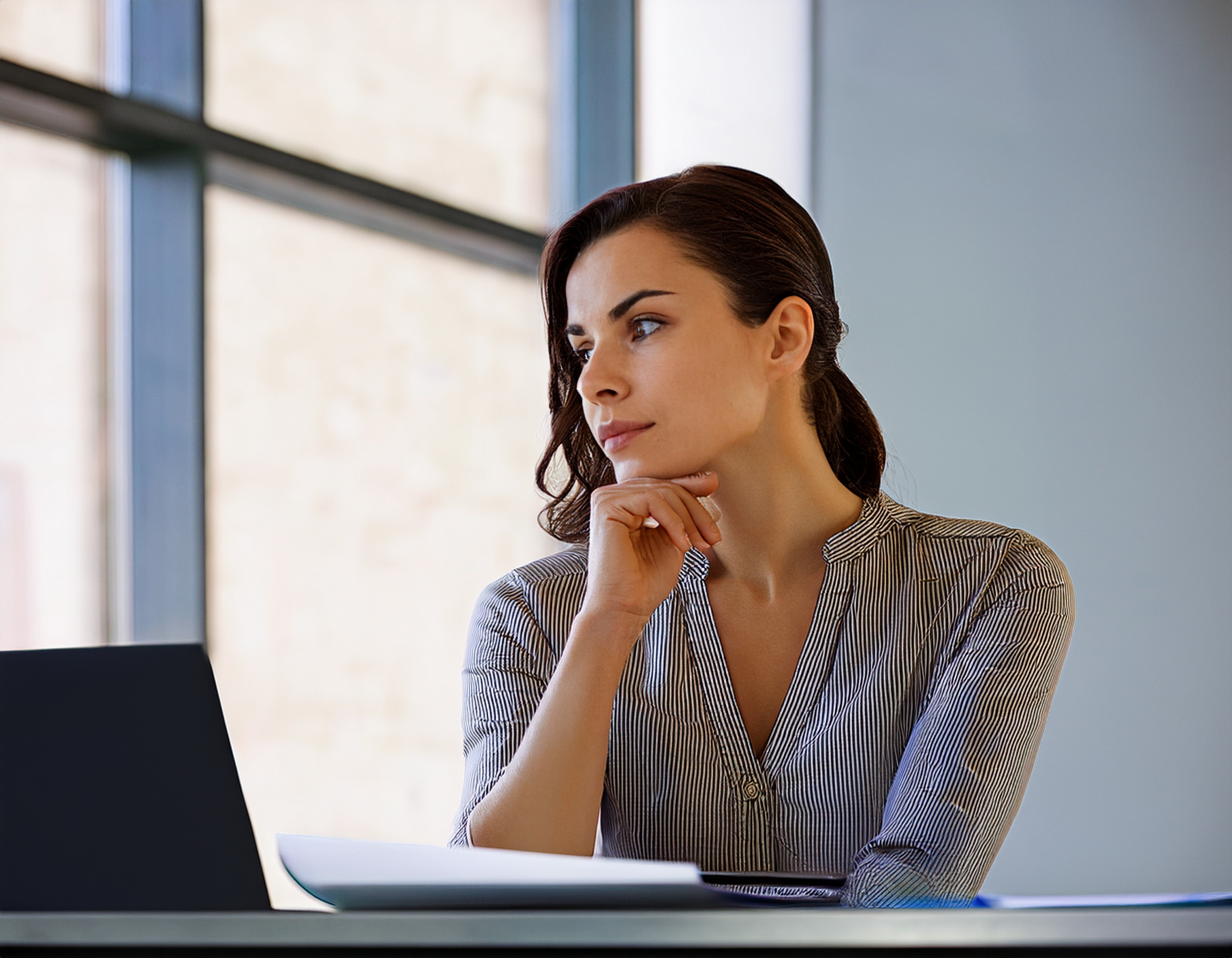 Geschäftsfrau mit selbstbewusstem Ausdruck im Arbeitsumfeld